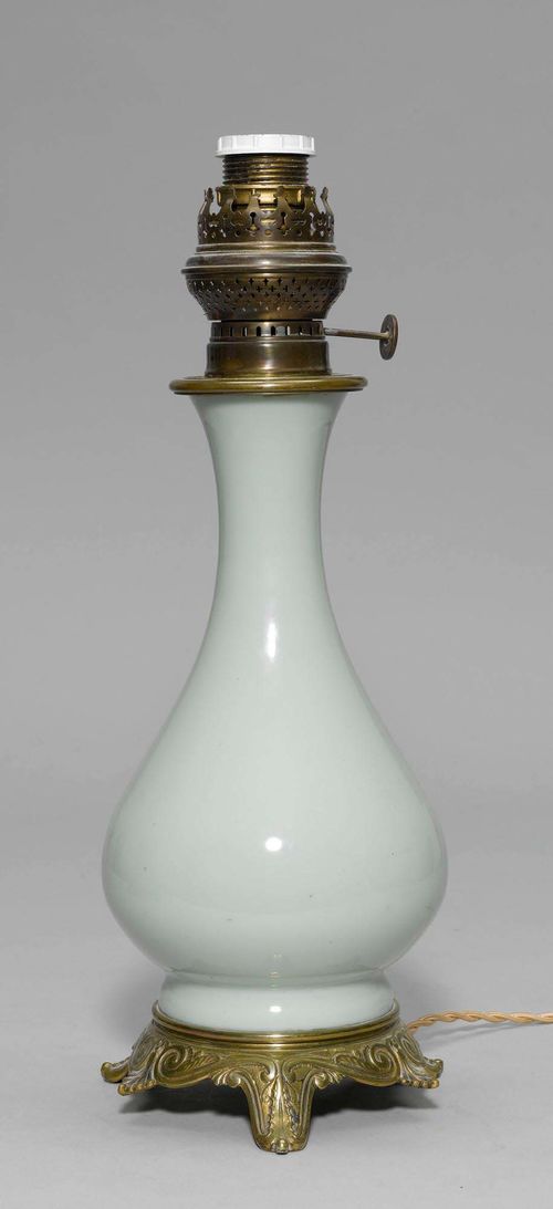 VASE AS A LAMP, 19th century. Light green porcelain, bronze and brass. On a round profiled base with 3 feet. H 45 cm.