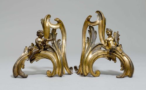 PAIR OF FIREPLACE CHENETS, Louis XV, 18th century. Bronze with remains of gilding. Volute form, each with 1 seated putto. H 27 cm.