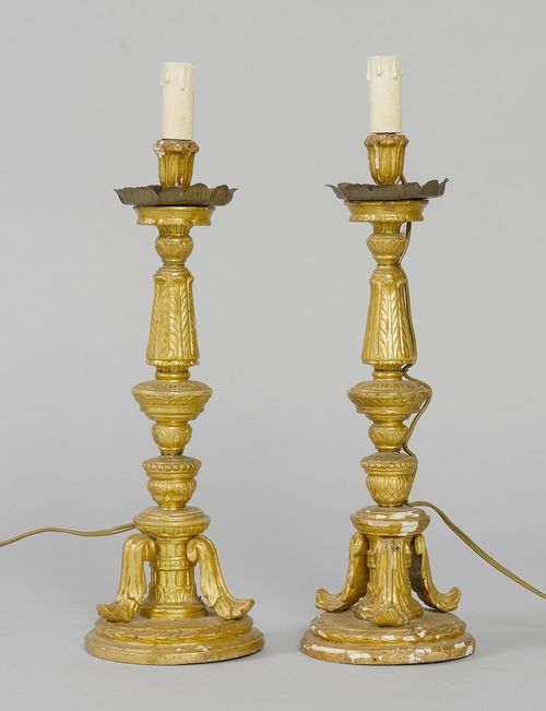 PAIR OF CANDLESTICKS AS TABLE LAMPS, late Baroque, Italy, 19th century. Wood, carved with leaves, leaf friezes, beading, and gilt. Turned shaft on a foot with 3 scrolled leaves. On a round base. H 41 cm. Fitted for electricity. Some losses.