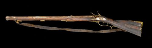 FLINTLOCK RIFLE, German, 18th century. Heavy octagonal barrel (L 82.5 cm), Cal. 16 mm, mark. Lock plate and cock, polished and curved. Brass decoration with dolphins, flowers and tendrils. Carved walnut stock. Ramrod, missing. Total length 121.5 cm. Requires restoration.