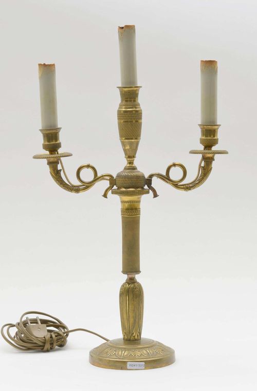 CANDELABRA, Restoration, Paris. Bronze, gilt. Round shaft with tall, vase-shaped nozzle. Scrolled light branches with round drip plates and nozzles. On a round base. H 41 cm. Fitted for electricity.