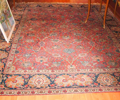 ISFAHAN old. Red ground, patterned throughout with trailing flowers and palmettes in harmonious colours, blue border with large flowers, slight wear, 305x235 cm.