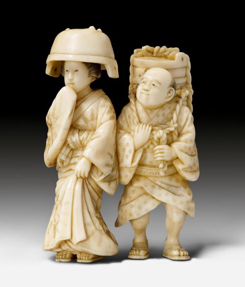 AN IVORY OKIMONO OF A COUPLE ON A ROAD, PARTLY ENGRAVED AND BLACKENED. Japan, Meiji Period, Height 7 cm.