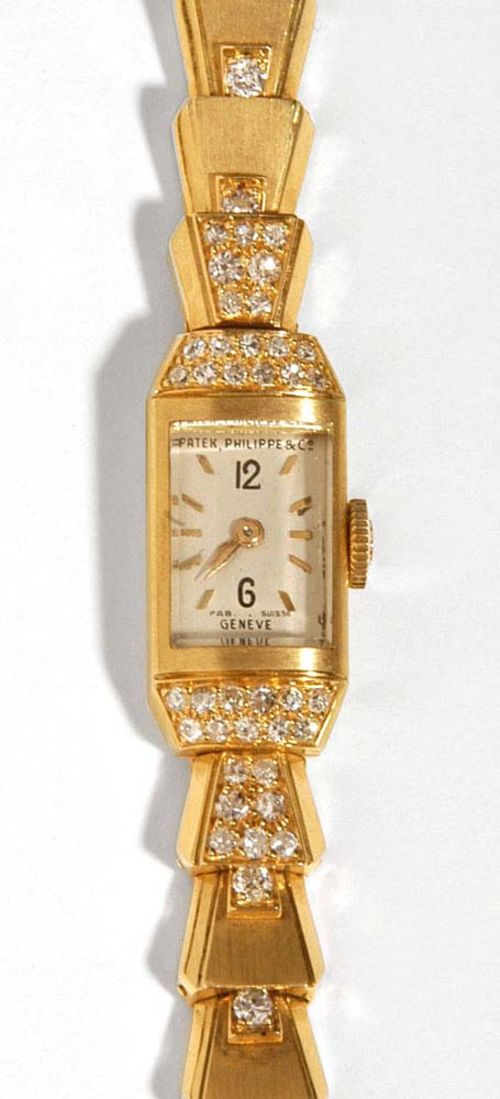 DIAMOND AND GOLD LADY'S WRISTWATCH, PATEK PHILIPPE, circa 1938/1985. Yellow gold 750. Case No. 504201 from 1938, bezel and lugs partly decorated with octagonal cut diamonds. Silver coloured dial with gold indices and hands. Movement No. 843.899, Cal. 8'''80 from 1957, assembled by Patek Philippe in 1985. Decorative bracelet with trapezoid segments each with 1 diamond. Total weight of diamonds ca. 1.10 ct, not original, France circa 1941. L ca. 16.5 cm. With extract from archive. Jan 2006