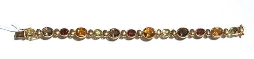 GEMSTONE AND GOLD BRACELET. Yellow gold 750. Casual elegant bracelet made of 13 different large, oval-shaped gemstones, such as citrines, garnets, smoky quartz and peridots, totaling ca. 20.00 ct. Additionally adorned with gold oval pieces. L 20 cm.