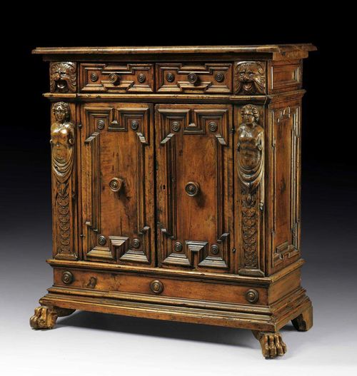 SMALL WALNUT CREDENZA, Renaissance, Tuscany, 17th century Finely carved with lions' heads, figural angles, frieze and paw feet. Double door at the front and two drawers. Wooden knobs. Some alterations. 85x36x93 cm.