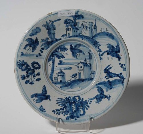 PLATE, Nevers, 2nd half of the 17th century. In Savona style. With a town view in blue. Verso with stylised foliate motifs. D 23.5cm. Minor wear to rim. Provenance: private collection, South Germany