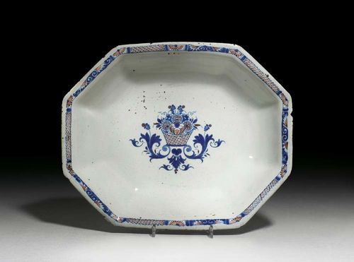 RECTANGULAR BOWL 'AU PANIER FLEURI', Rouen, circa 1720-40. Painted in blue and iron red with a basket of flowers over acanthus console. D 31.5cm. Wear to edge and slight flaking of glaze on the edge. Provenance: private collection, South Germany