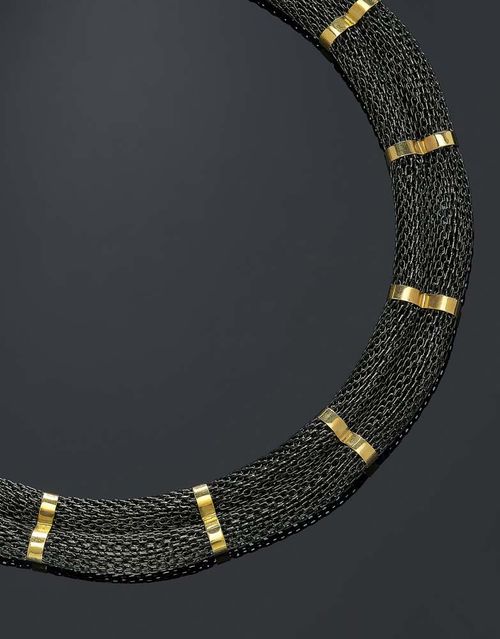 GOLD AND STEEL NECKLACE, DONNA GIOIELLI, Florence ca. 1990. Yellow gold 750 and steel. Decorative necklace in the shape of a rolled, finely braided, blackened steel band, adorned with 11 gold bands. Yellow gold fastener. L ca. 44 cm, W 1.6 cm.