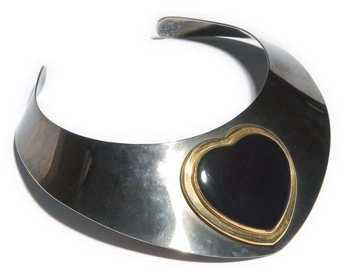 STEEL, GOLD AND ONYX CHOKER. Steel and yellow gold 750. Broad, blackened choker with a tapered top, set with a large onyx heart in a gold setting. Ø ca. 11.2 cm. W 2.1-6.5 cm.