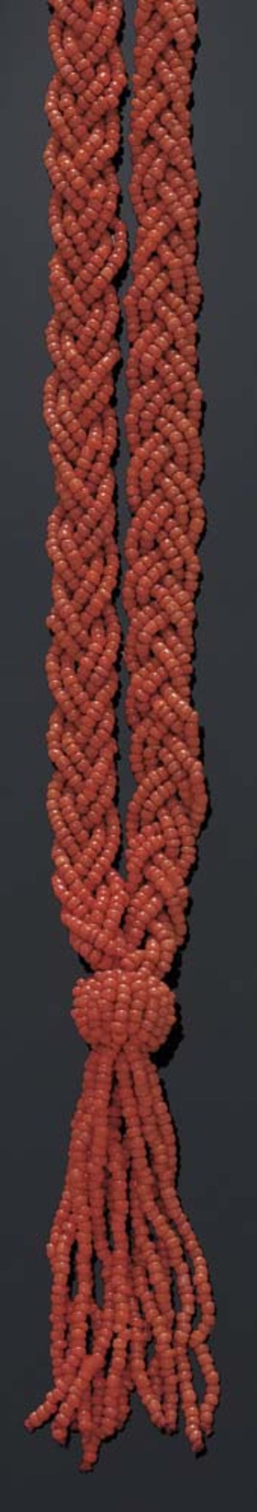 CORAL SAUTOIR WITH BRACELET, ca 1910. Bracelet fastener yellow gold. Long, double-row necklace with a braid pattern and ending in a tassel, with numerous small orange-red coral beads, L ca. 75 cm. Matching breaded bracelet made of small coral beads, W 3.3 and L ca. 17 cm.