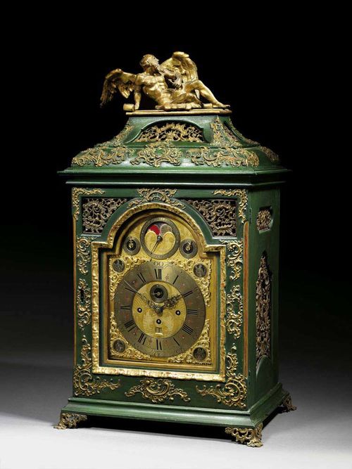PAINTED CLOCK WITH CARILLON AND MOONPHASES, Baroque, the dial signed XAV BAYER IN OLLMÜTZ (Xaver Bayer, active circa 1740/60), Ollmütz circa 1740. Finely carved wood, painted green and gilded. The case with Chronos atop, set on shaped plinth with pierced scrolled feet. Finely pierced gilt bronze dial and silver plated bronze chapter ring, also with 2 small rings for seconds and date, also 3 further rings: the centre ring with finely painted moon phases, the other rings for striking and music mechanisms. Fine brass movement with verge escapement and 4/4 striking on 2 bells, on the hour the carillon with 14 chimes. Trip repeat. 44x33x85 cm. Provenance: Swiss private collection.