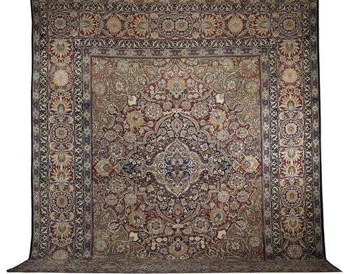 KIRMAN antique. Floral central medallion in red, blue and white on beige ground, the whole carpet lavishly decorated with trailing flowers and palmettes in bright colours,  broad border in red with flowers and leaves, some  wear, 465x400 cm.