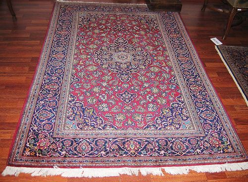KESHAN old. Red ground with blue central medallion decorated with trailing flowers in harmonious colours. Blue border. Good condition. 212x134 cm.