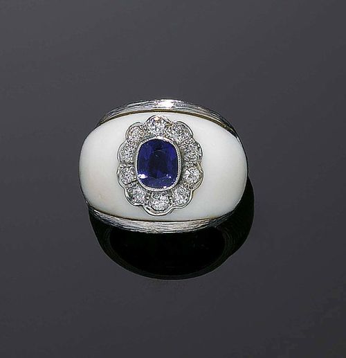 SAPPHIRE AND DIAMOND RING, BINDER. White gold 750. Convex band ring, the top is set with 1 oval sapphire of ca. 0.80 ct. surrounded by 10 brilliant-cut diamonds, totalling ca. 0.30 ct,  flanked by cut ivory pieces. Size ca. 48.