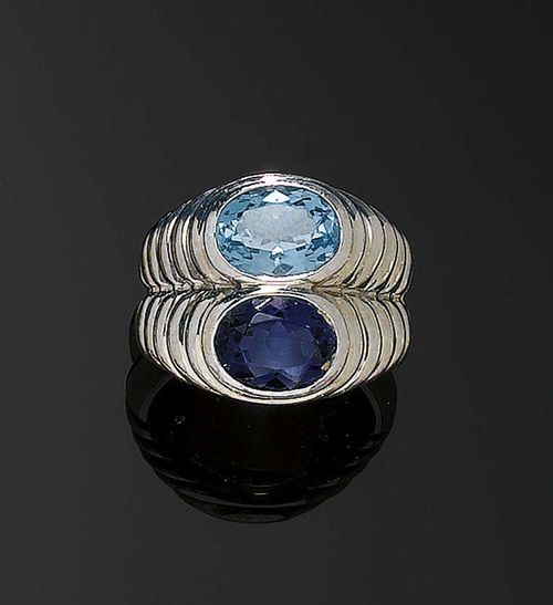 IOLITE AND TOPAZE RING, BULGARI. White gold 750. Casual-elegant double-ring, the ribbed top is decorated with 1 oval iolite of ca. 1.50 ct and 1 oval blue topaz, treated, of ca. 2.20 ct. Signed. Size 50.