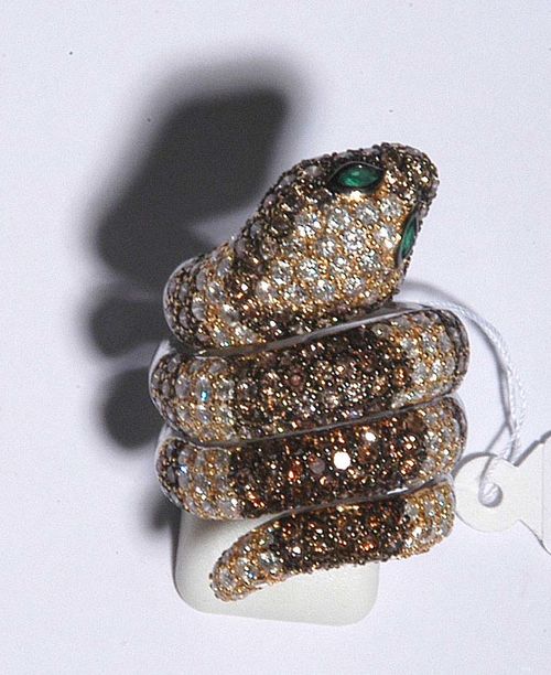 BRILLIANT-CUT DIAMOND AND EMERALD RING. White gold 750. Highly decorative ring in the shape of a snake wrapped around a finger, the top is set with 241 cognac-coloured and colourless brilliant-cut diamonds totalling ca. 5.00 ct as well as two navette-cut emeralds totalling ca. 0.13 ct for eyes. Size ca. 57.