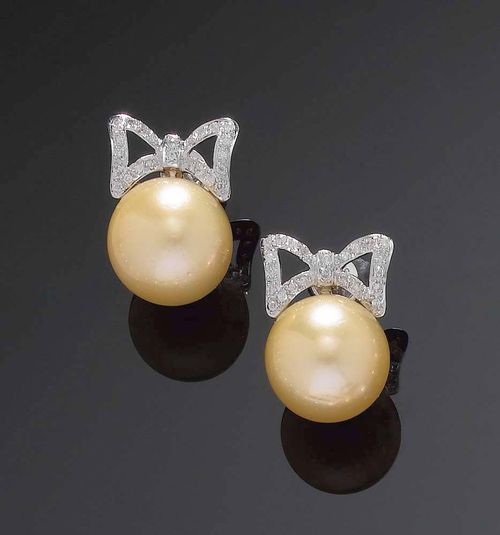 PAIR OF SOUTH SEA CULTURED PEARL AND DIAMOND PENDANT EARRINGS. White gold 750. The 2 gold-colour pearl pendants measuring ca. 14 mm Ø, each supported by a bow set with brilliant-cut diamonds, totalling ca. 0.20 ct.