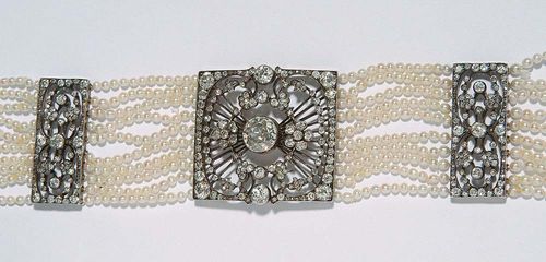 DIAMOND AND PEARL BRACELET, ca. 1900. Silver over rosé gold. Very fancy bracelet with 10 rows of small Oriental pearls of ca. 2 mm Ø, the square open-worked mid-section is decorated with voluta and floral motifs and set with 1 old-mine-cut diamond of ca. 1.70 ct and numerous additional diamonds. The rectangular fastener and the 2 lateral decorative elements are correspondingly worked and decorated with diamonds. With a total of 428 diamonds totalling ca. 8.00 ct. L ca. 18.5 cm. Thread torn at one point.