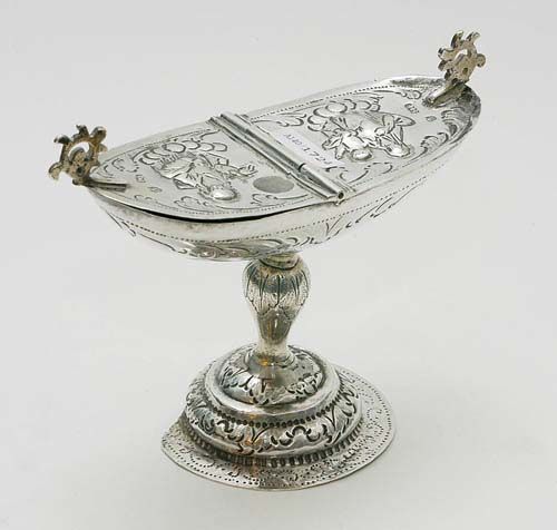 INCENSE BURNER. Probably Venice, 2nd half of the 18th century.Boat-shaped bowl with a hinged lid. Open-worked, small handles on both sides. Chased image of Mary and a saint. Body with foliate engraving over stepped and chased round hollow foot with node. 18x7 cm. 240 g. Considerable repairs.