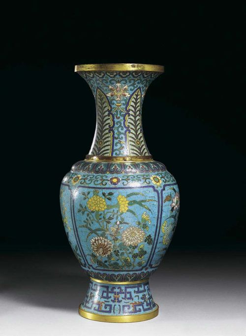 CLOISONNÉ VASE with a high base and a trumpet-like neck which curves outwards. On a turquoise background, four cartouches are depicted with flowers from the four seasons. On top, there is a band of intertwined flowers and a wreath of lotus leaves. The neck shows lancet-shaped leaves and classical lotus tendrils, the base shows archaic-looking geometric dragon curves. Base, inside of the neck, rims. China, around 1800, H 47.5 cm. Slightly restored, gold partially rubbed off. Berti Aschmann Collection.