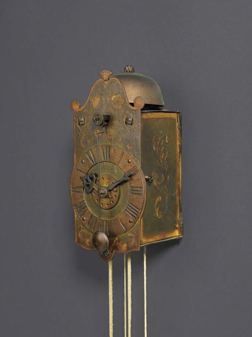 SMALL PAINTED IRON CLOCK WITH FRONT PENDULUM AND ALARM, Baroque, South German circa 1700. Floral and foliate painted dial with copper chapter ring, verge escapement and alarm striking on bell. Alterations. 10x10x19 cm. Provenance: O. Honegger collection  Zurich.