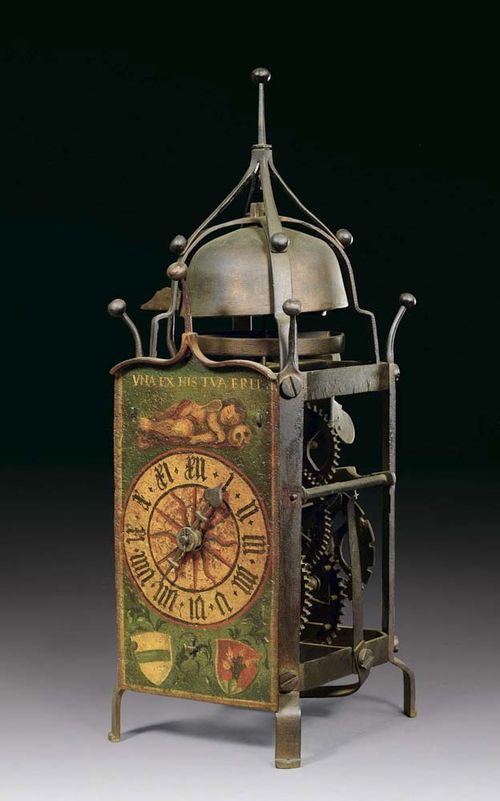 PAINTED HOUSE CLOCK, Gothic, probably Zug circa 1550. Open prism-shaped case with pinnacle terminal, shaped dial with putto under motto UNA EX HIS TUA ERIT and coats of arms. Movement with wheel balance and striking mechanism, also count wheel with gears inside. With restorations. 14x15x41 cm. Provenance: O. Honegger collection  Zurich.