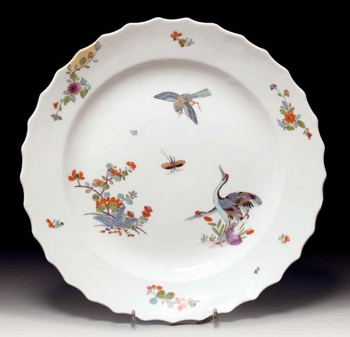 DISH WITH CRANE MOTIF, Meissen, circa 1725-30.Painted in Kakiemon style with 2 cranes, Indianischer Blumen, a bird in flight and an insect. With Indianische Blumen on the rim. Underglaze blue sword mark. D 28.5 cm. With visible repair to small flake on the rim, flat chip on back of rim, minor rubbing. Provenance: from a private collection, Solothurn
