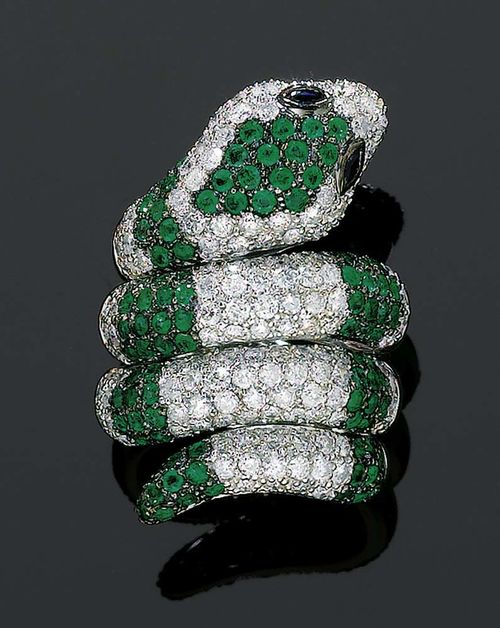 EMERALD, DIAMOND AND SAPPHIRE RING. White gold 750. Very decorative, modern ring in the shape of a coiled snake, the top completely set with 95 emeralds totalling ca. 2.00 ct and 148 brilliant-cut diamonds totalling ca 3.00 ct. The eyes consist of two sapphire navettes totalling ca. 0.15 ct. Size ca. 56.