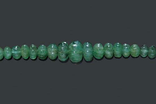 EMERALD NECKLACE. Decorative necklace consisting of numerous graduated engraved emerald rondelles of ca. 3-11.5 mm Ø, totalling ca. 129.00 ct. On green/gold cordon. Adjustable length.