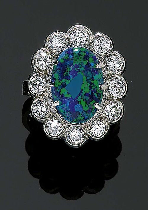 OPAL AND DIAMOND RING, ca. 1940. White gold 585. Classic-elegant ring, the top set with 1 fine, blue-green black opal of ca. 14 x 10 mm, surrounded by brilliant-cut diamonds totalling ca. 1.20 ct. Size 53.