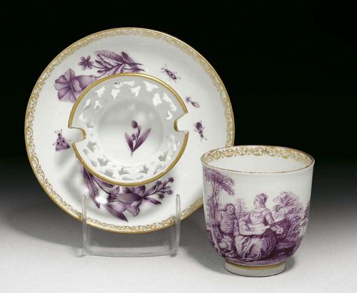TREMBLEUSE CUP AND SAUCER, Meissen, circa 1745. Painted in purple camaïeu, the cup with a Watteau scene, the saucer with a pierced stand painted with ombrierte flowers and insects, rims with gilt lace borders, crossed swords in underglaze-blue, impressed numeral 6 to cup, painters mark G in gilding, associated.