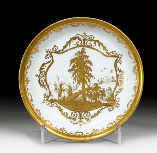 SAUCER WITH ENGRAVED LANDSCAPE IN GOLD, Meissen, circa 1725.From the workshop of Abraham Seuter decorated in gold with a scene of two hunters in a forest landscape. Augsburg border. No mark. D 12.6cm. Glazing fault on the back. Somewhat rubbed. Provenance: from a private collection, Solothurn.