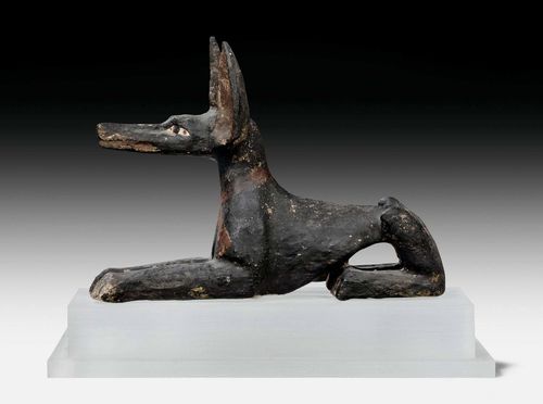 PAINTED FIGURE OF ANUBIS,Egypt, probably Deir el-Medina, 6th/4th century BC. Painted wood. Recumbent Anubis with collar. On a rectangular plastic base. L 21 cm.
