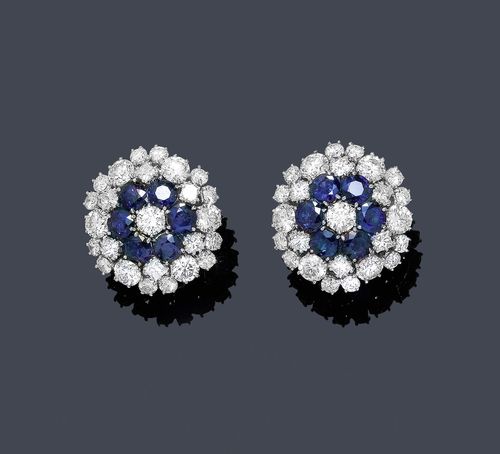 SAPPHIRE AND DIAMOND EAR CLIPS. White gold 585. Decorative, flower-shaped ear clips with studs, each set with 6 round sapphires, weighing ca. 4.40 ct, and set throughout with 25 brilliant-cut diamonds weighing ca. 7.90 ct. Matches the following lot.