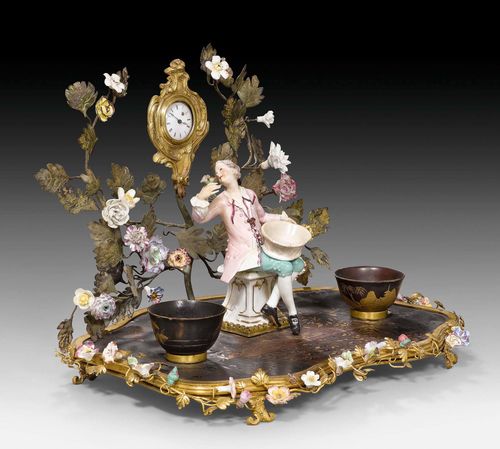 ENCRIER WITH LACQUER PAINTING, PORCELAIN FIGURE AND CLOCK,Louis XV and later, Paris, 18th/19th century. Matte and polished gilt bronze, polychrome porcelain from Saxony and Vincennes, and "gout chinois" lacquer painting. The clock with enamel dial and pocket watch movement. Some restoration required. 40x26x38 cm. Provenance: from a highly important Swiss private collection.