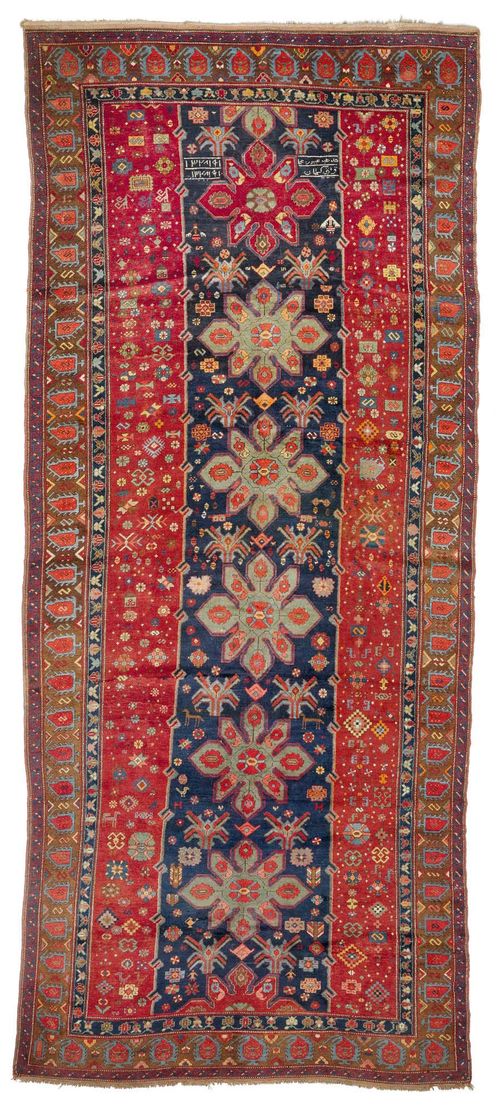 CAUCASIAN old.Red and blue central field geometrically patterned with stars and blossoms in harmonious colours, brown border with boteh motifs, 180x410 cm.