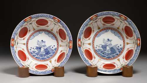 A PAIR OF IMARI-STYLE BOWLS SHOWING A SCHOLAR ON A CARP LEAPING FROM THE WAVES. Japan, Arita, 19th c. D 23 and 24 cm. Wooden stands. (2)