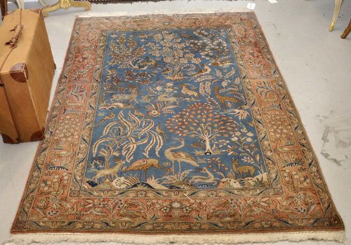 GHOM old.Blue central field patterned with plants and animals in harmonious colours, pink edging, slight wear, 137x200 cm.