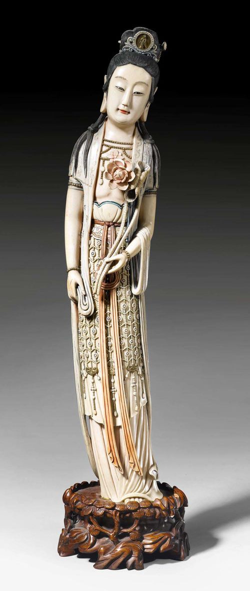 A PARTLY COLOURED IVORY FIGURE OF GUANYIN HOLDING A LOTUS FLOWER. China, 19th c. Height 58.5 cm (without base).