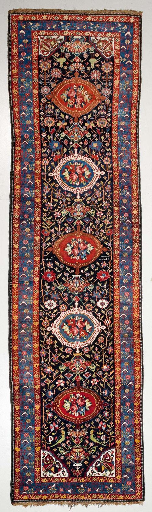 BACHTIAR antique.Black central field with five rose medallions, opulently patterned with stylised plants and birds, blue border, 130x450 cm.