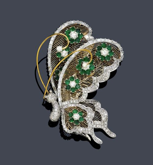 EMERALD AND DIAMOND BROOCH / PENDANT, ca. 1950. Yellow and white gold 750. Decorative brooch "en tramblant" designed as a butterfly, the body set with numerous single-cut diamonds weighing ca. 0.40 ct in total, the wings of fine gold wires, each decorated with 7 blossom motifs with 42 emeralds weighing ca. 1.00 ct in total, framed by 70 baguette-cut diamonds and numerous single-cut diamonds weighing ca. 1.60 ct in total. L ca. 8.5 cm.