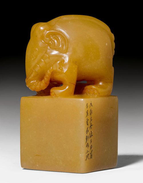 A SQUARE SOAPSTONE SEAL SURMOUNTED BY AN ELEPHANT, WITH CARVED SEAL SURFACE AND A TWO-LINE INSCRIPTION ON ONE SIDE.