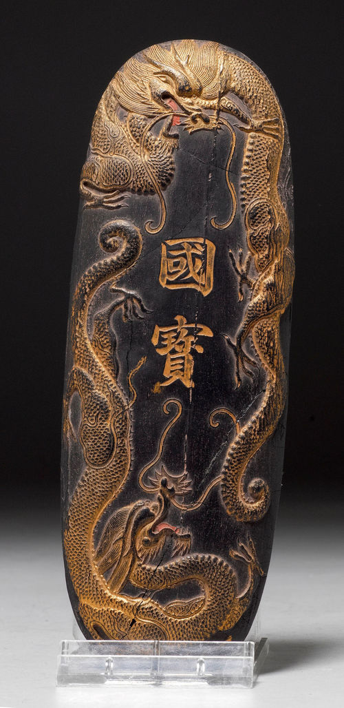 AN OVAL INKSTONE WITH GILT INSCRIPTION: “GUO BAO” (NATIONAL ART TREASURE) FLANKED BY DRAGONS IN RELIEF.