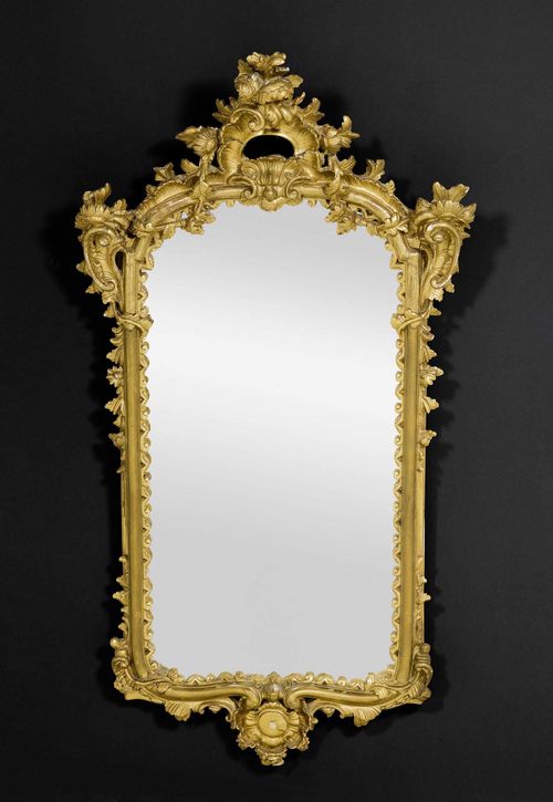 MIRROR,Louis XV, Genua circa 1750. Carved, gilt and partly pierced wood. Old mirror plate. Restorations and some losses. H 69 cm, W 29 cm.