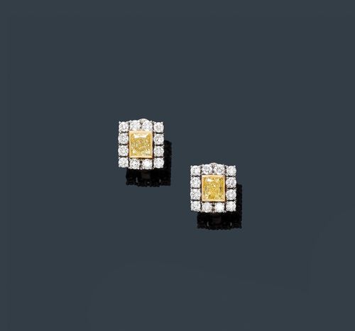 FANCY DIAMOND EAR CLIPS. White gold 750. Classic-elegant ear clips with studs, each set with 1 yellow diamond, weighing 2.23 ct in total, Fancy Intense yellow, radiant cut, within a border of brilliant-cut diamonds weighing ca. 0.96 ct in total. With GIA Report No. 2155351950, and No. 215688247, April and September 2013, respectively.