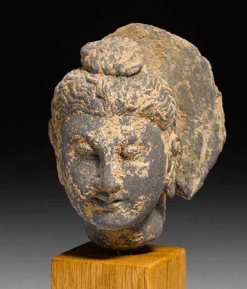 A SMALL GREY SCHIST BUDDHA HEAD. Gandhara, ca. 3rd c. H 8.5 cm. Mounted in a plinth.