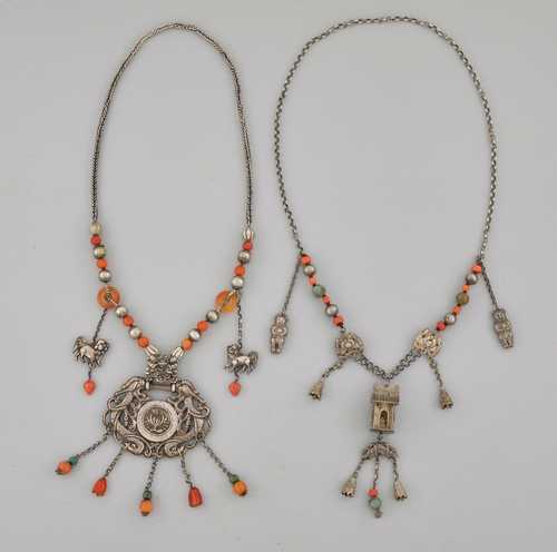 TWO NECKLACES OF SILVER, CARNELIAN AND TURQUOISE. China, L 50 cm (amulet 10 cm) and 57 cm. a) Amulet in the form of dragons with a floral medallion. b) Pendant shaped as a shrine with deity.