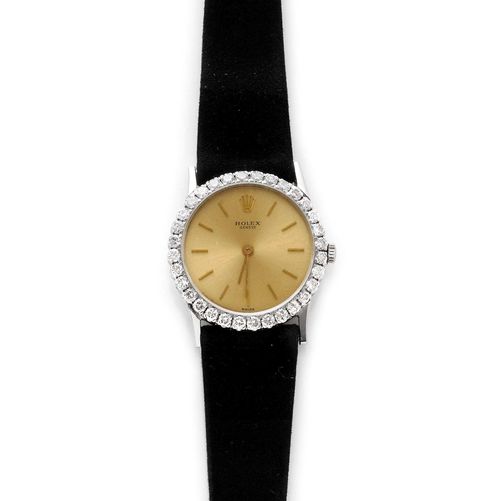 DIAMOND LADY'S WRISTWATCH, ROLEX, 1950s. Yellow gold 750. Ref. 3532. Round, extra-flat case No. 1521096, with diamond lunette weighing ca. 0.60 ct. Gold-coloured dial with applied indices and baton hands, signed Rolex Geneva. Hand winder, extra-flat movement Cal. 650. Black velvet band with silver-coloured clasp.