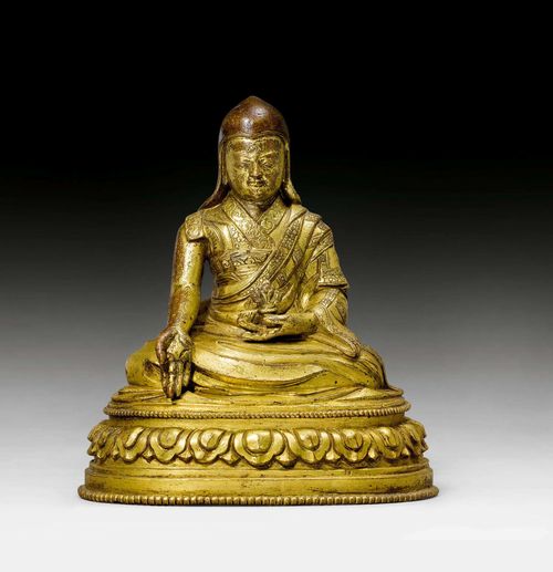 A GILT COPPER FIGURE OF A HIGH LAMA. Tibet, 17th c. Height 13 cm. Inscription. Sealed.